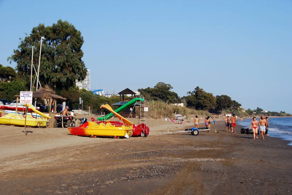 MARBELLA, SPAIN - Tourists relaxing on Funny Beach with pedaloes to the left hand side Marbella Malaga Province Andalusia Spain Western Europe
