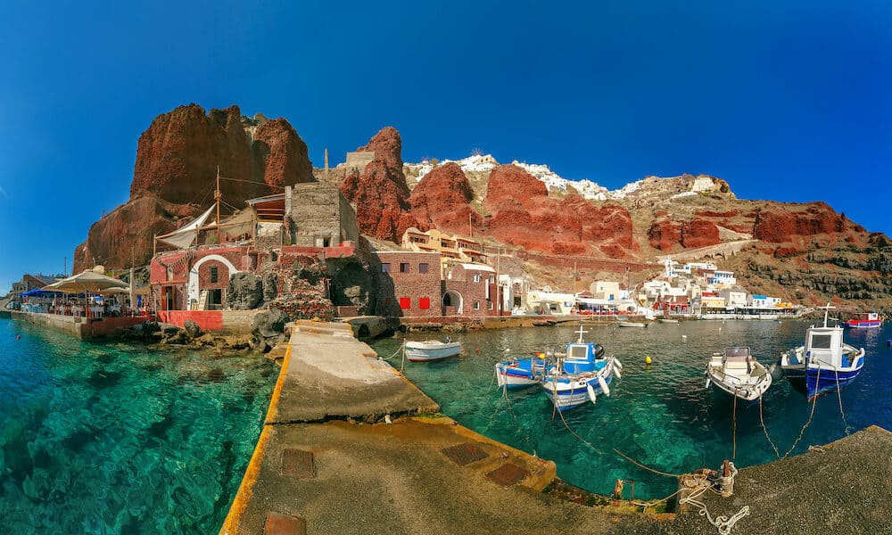 Panoramic view with fishing boats at Old port Amoudi of Oia village at Santorini island in Aegean sea, Greece