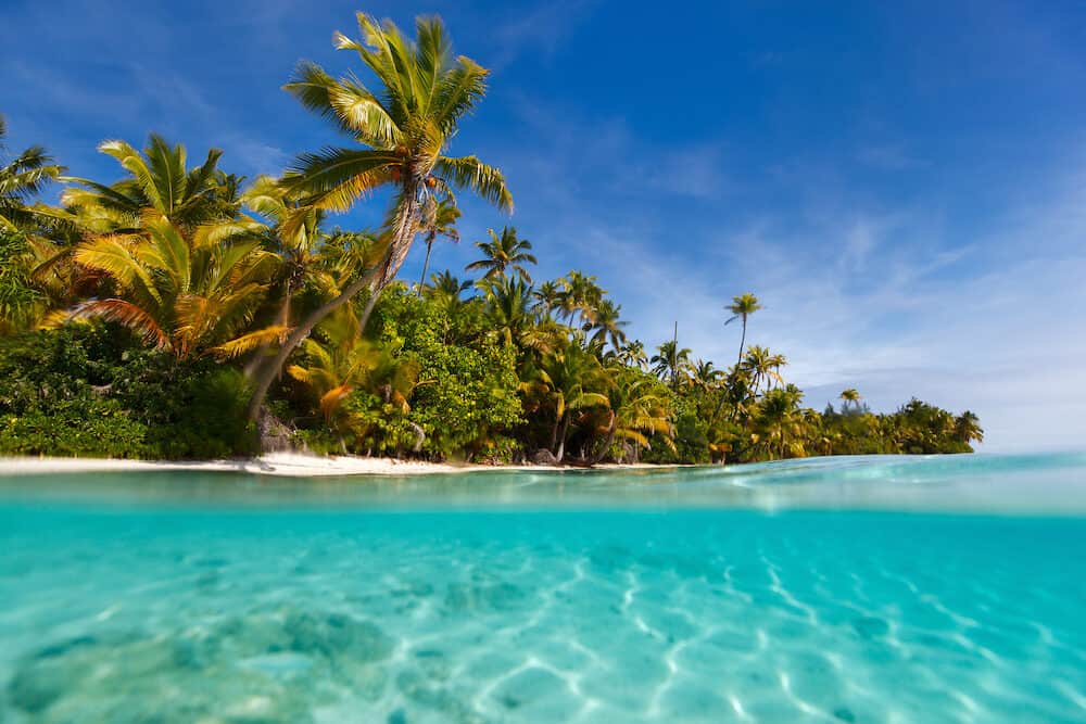 Stunning One Foot island in Aitutaki, tropical island with palm trees, white sand, turquoise ocean water and blue sky at Cook Islands, South Pacific