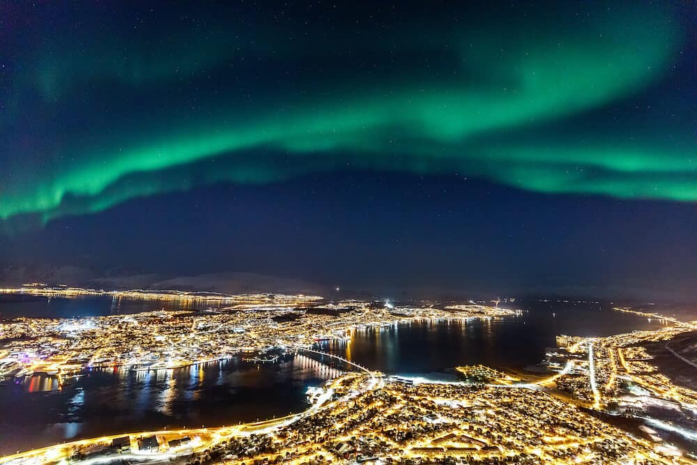 Incredible Northern lights Aurora Borealis activity above town of Tromso in Northern Norway