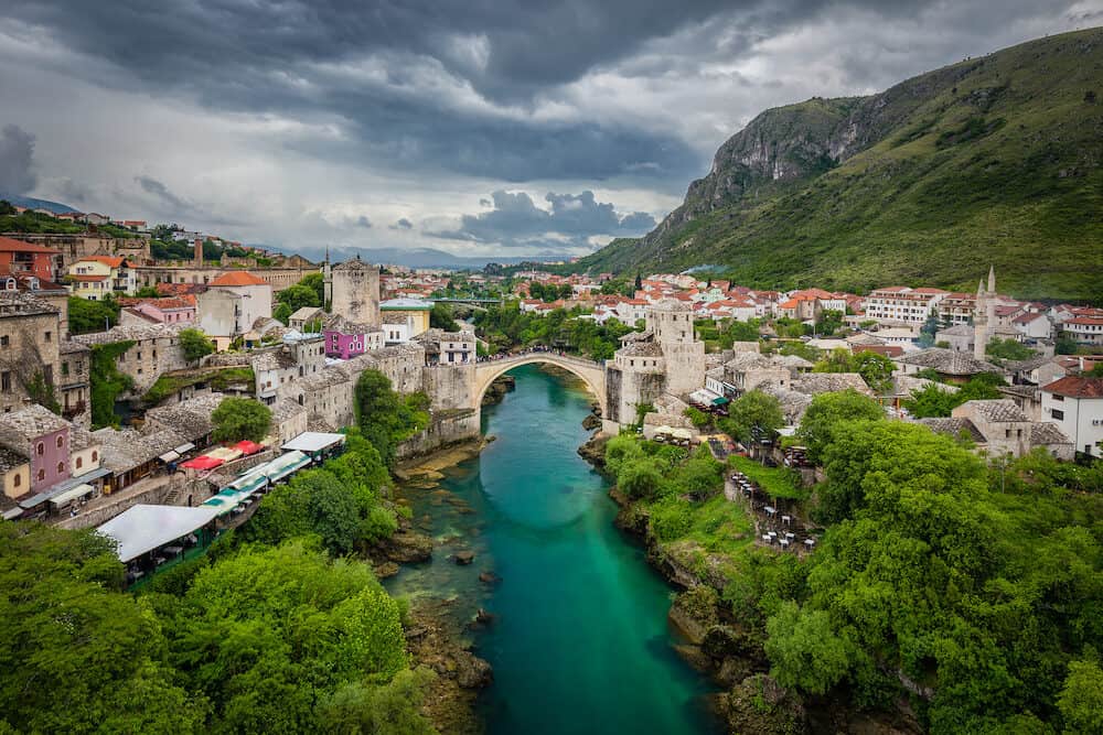 Panoramic aerial view of the historic town of Mostar with famous Old Bridge (Stari Most), a UNESCO World Heritage Site since 2005, on a rainy day with dark clouds in summer, Bosnia and Herzegovina