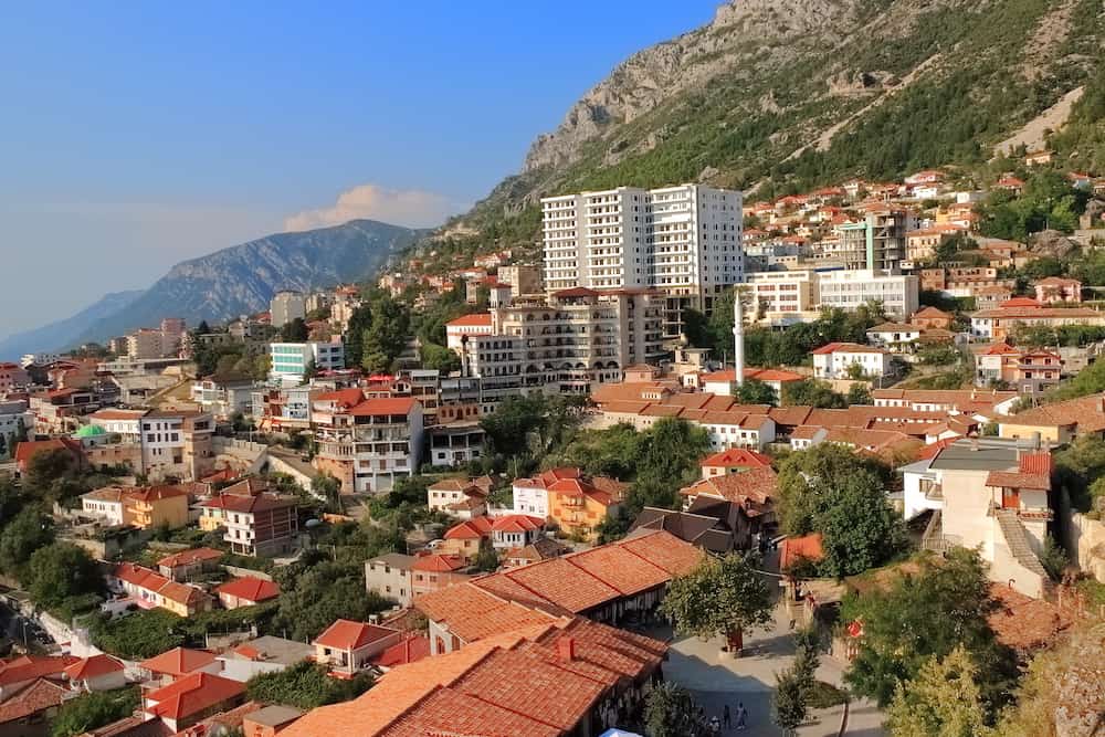 Panorama of the city of Kruja in central Albania from the hill with a medieval citadel overlooking modern residential buildings against the backdrop of the mountains.