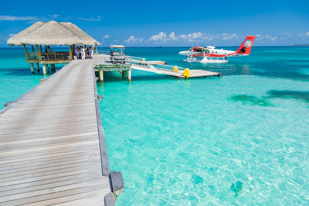 Ari Atoll, Maldives: Exotic scene with seaplane on Maldives sea landing. Vacation or holiday in Maldives concept background