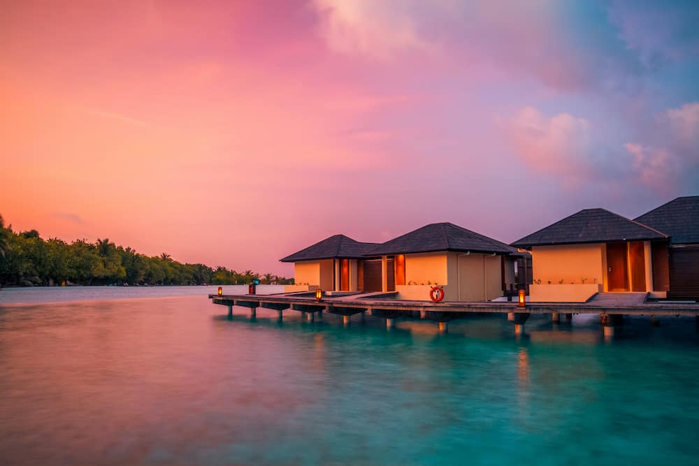Maldives island sunset. Water bungalows resort at islands beach. Indian Ocean, Maldives