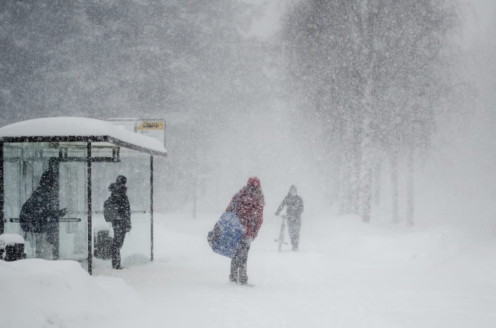 OULU, FINLAND - People standing on a bus stop during a snow storm