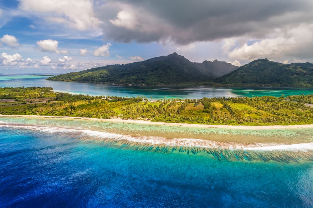 Aerial French Polynesia luxury travel honeymoon destination. Beach vacation at motu island of Huahine, Tahiti, Oceania adventure. View from above of paradise, French Polynesia, South Pacific Ocean.