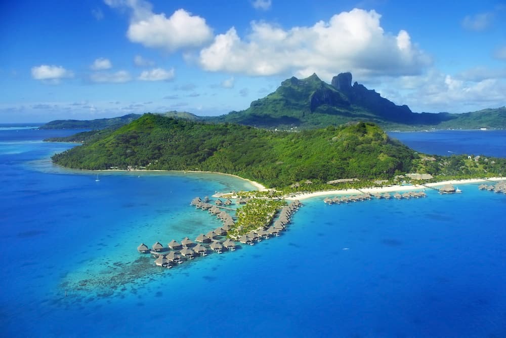 Aerial View of Bora Bora with Mount Otemanu in background and coral reef.