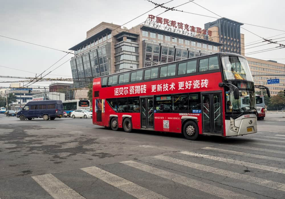 Beijing, China - Red bus traversing intersection at the 700-year-old Wangfujing Street crossing. Dongsi West Street is at right; Meishuguan East Street is to the left. Ahead is the Civil Aviation of China building.