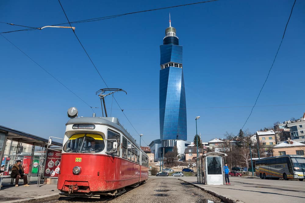 SARAJEVO, BOSNIA - Tram ready for departure on the train station stop, the Avaz Twist Tower is seen in the background. The tower is the highest in former Yugoslavia