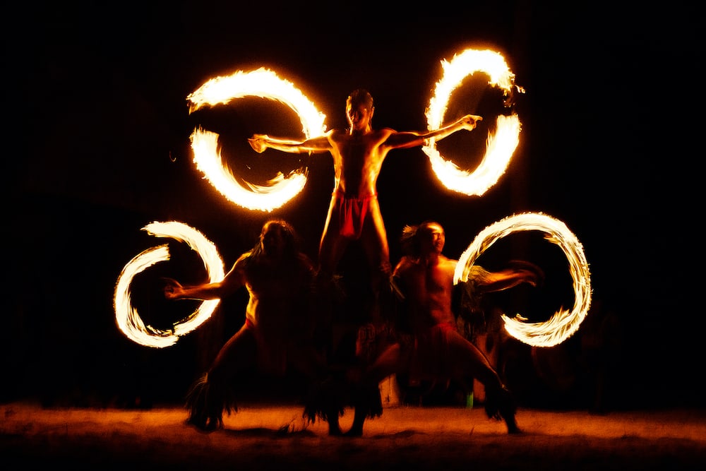 French Polynesia fire dance silhouettes of professional dancers at night on beach resort tiki party.