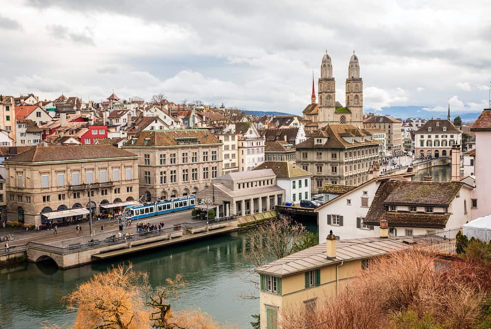 Beautiful panoramic view of historic city center of Zurich with famous Grossmunster Church, Helmhaus and Munsterbucke bridge crossing river Limmat on a cloudy winter day, Canton of Zurich, Switzerland.
