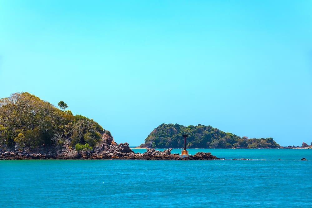 Lighthouse on the shoals of a small island on the way to the Saladan Pier bay in the bright scorching sun with turquoise green blue sea. Adaman sea, Koh Lanta, Krabi, Thailand.
