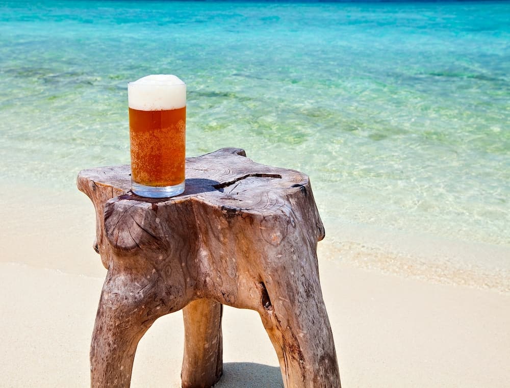 Glass of beer is on original beach table