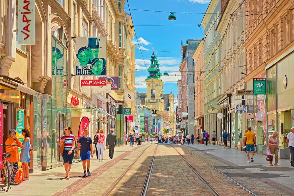 Linz - Austria: View through the main street of the city with walking people, shops, and tram lines