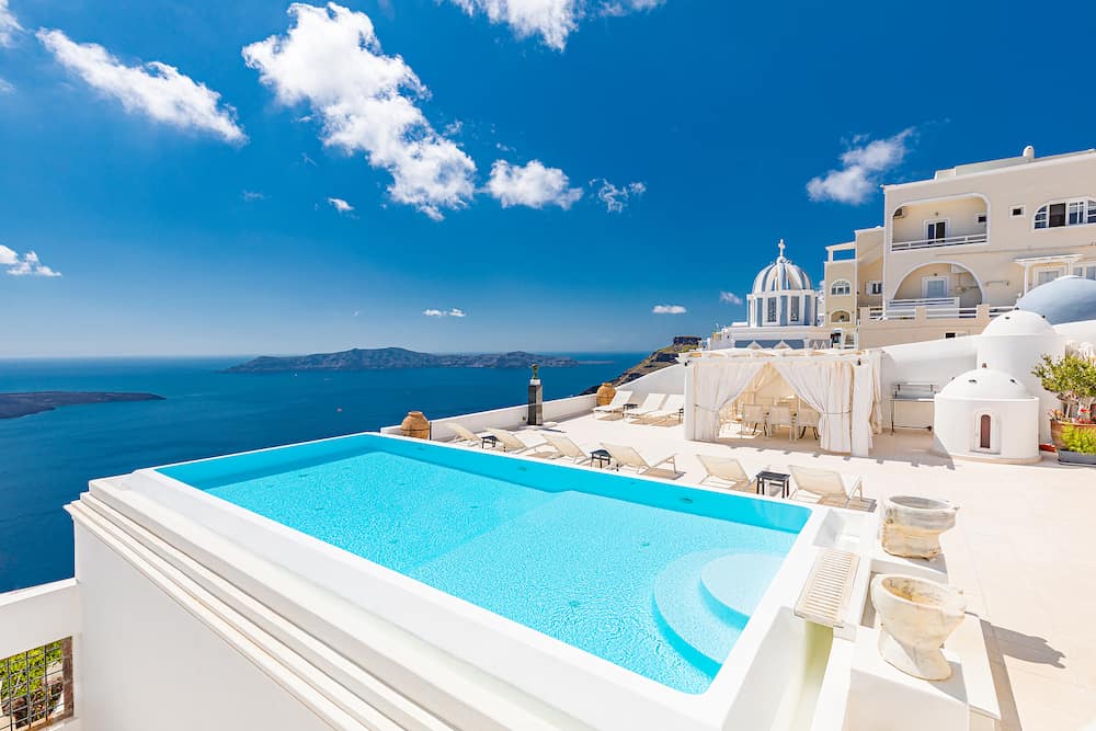 Santorini Greece, view over empty infinity pool Santorini. Luxury summer travel vacation, exotic honeymoon and couple destination. Caldera with blue sea bay and volcano view. Relax summer holiday