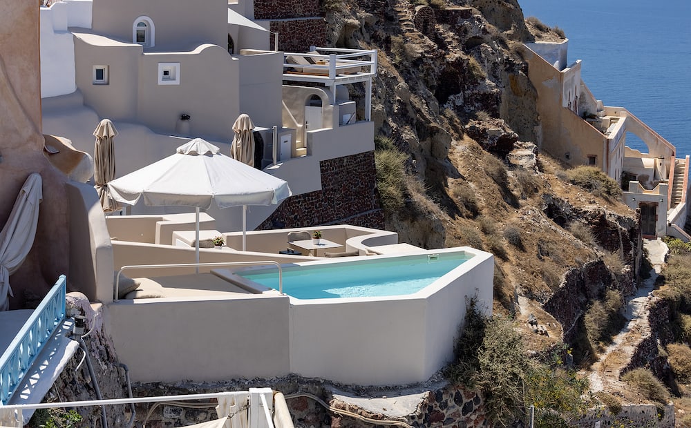 Oia, Santorini, Greece - Whitewashed houses with terraces and pools and a beautiful view in Oia on Santorini island, Greece