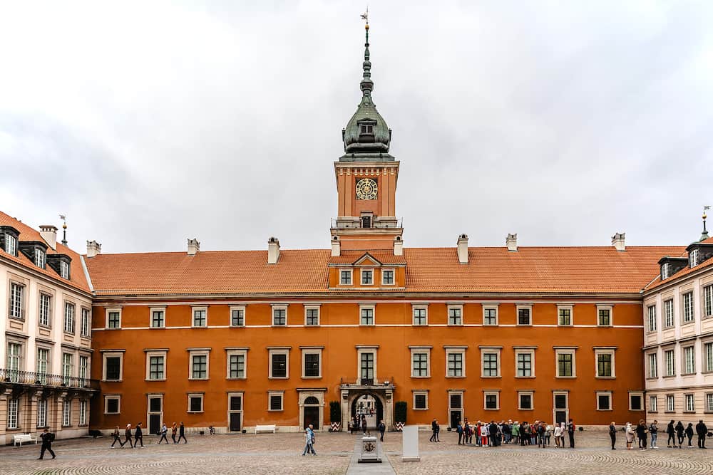 Warsaw,Poland-Court of the Royal Castle with Sigismund tower situated in Castle Square,entrance to Old Town,facade built of bricks.Polish royal residence.People standing in line.