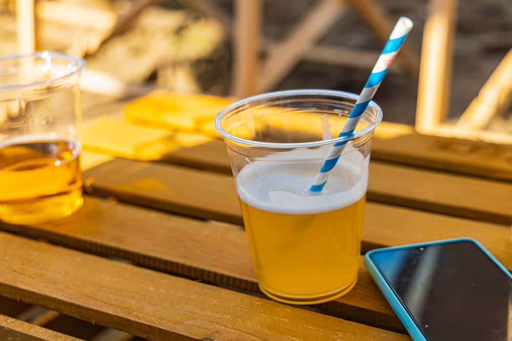 Beers with colorful straw and smartphone lie on wooden table made from crate