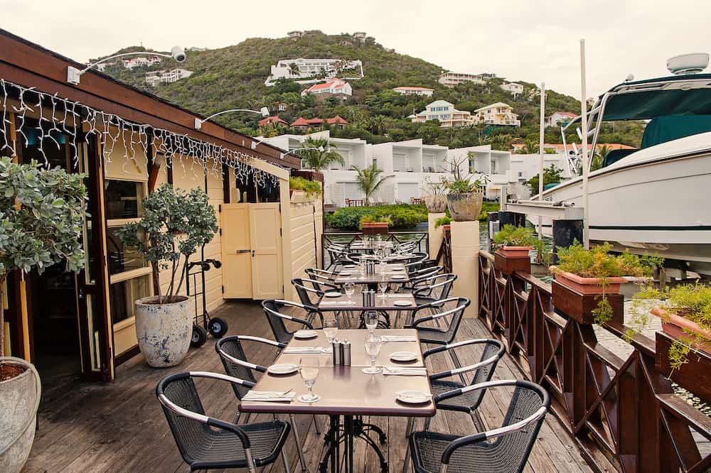 Restaurant open air in philipsburg, sint maarten. Terrace with tables, chairs and yacht in sea. Eating and dining outdoor. Summer vacation at Caribbean island, travelling. Enjoy life concept.