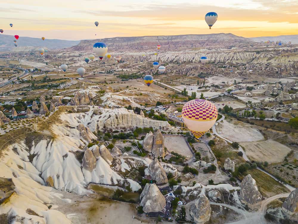 Spectacular drone view of hot air balloons ride over Turkeys iconic Cappadocia, the underground cities and fairy chimneys valley, rock formations. 