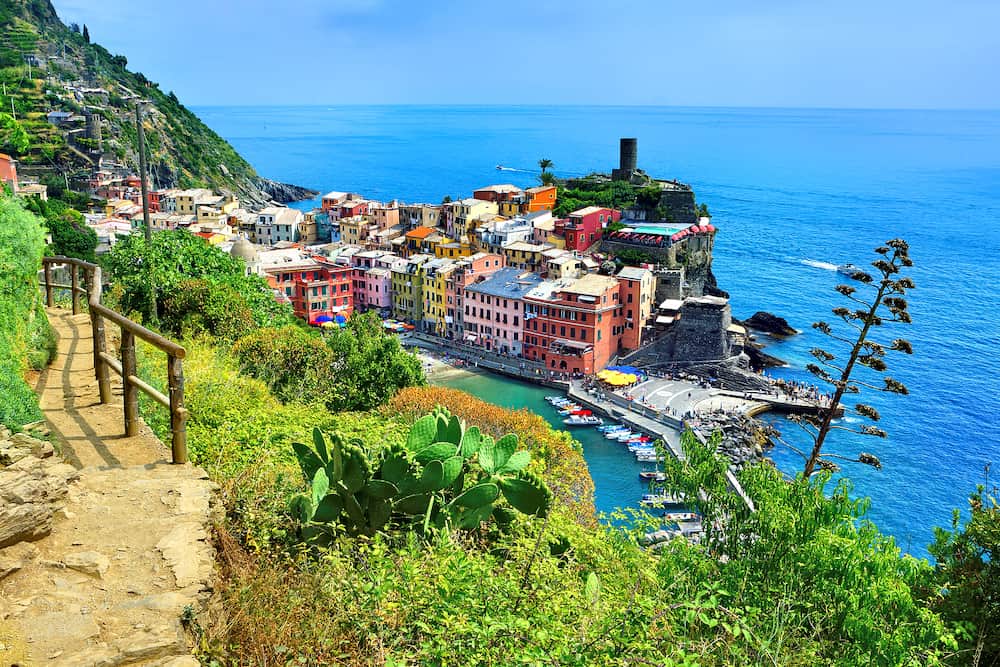 Colorful Cinque Terre village of Vernazza, Italy. Above view with hiking trail and blue sea.