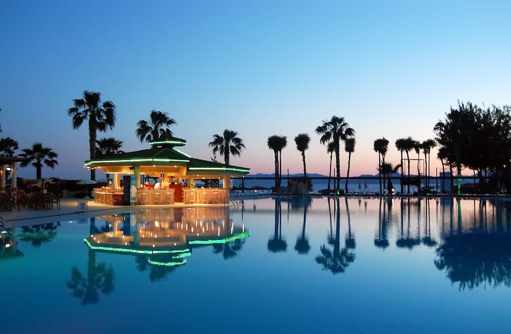 Fethiye, Turkey - View of the pool, pool bar and palm trees at sunset in hotel Club Tuana Fethiye.