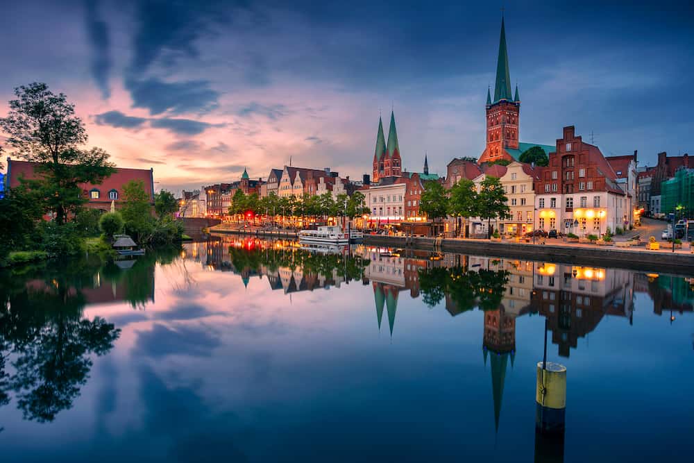 Lubeck, Germany. Cityscape image of riverside Lubeck with reflection of the city in Trave River at sunset.