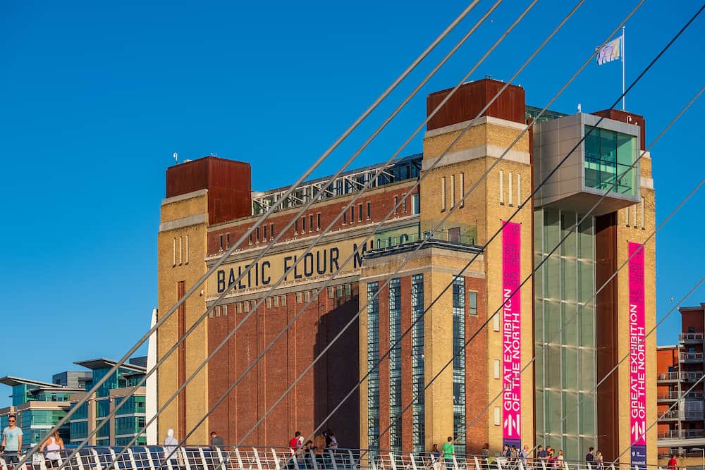 Newcastle, England - The Baltic Centre for Contemporary Art behind Gateshead Millennium Bridge on a beautiful summer afternoon.