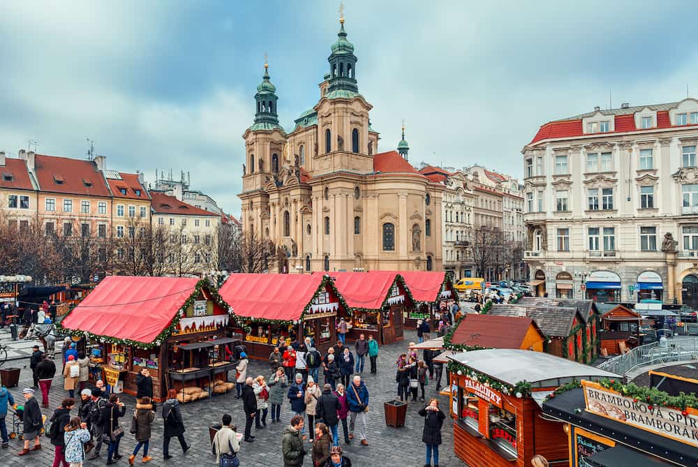 PRAGUE, CZECH REPUBLIC - People walking among wooden stalls with souvenirs and traditional food at Christmas market taking place each year on December on Old Town Square of Prague.