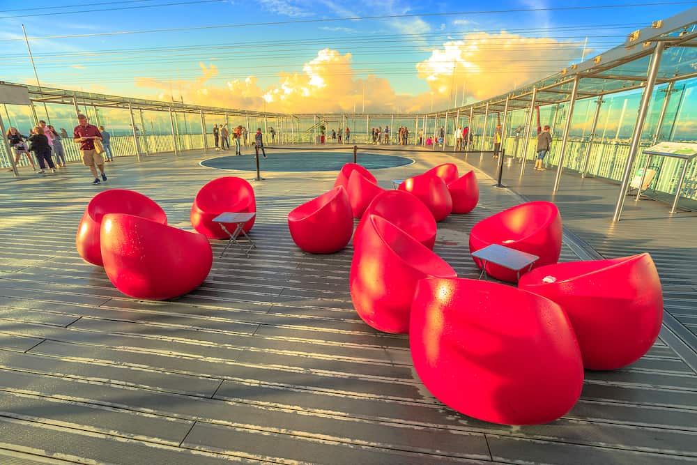Paris, France - red modern armchairs in foreground on the panoramic terrace of Tour Montparnasse Observation Deck. People looking skyline on top of the highest skyscraper in Paris.