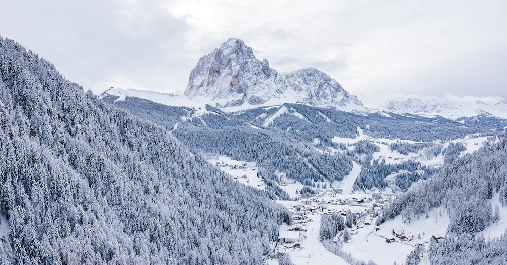 Slope on the Alpine skiing resort Val Gardena in Italy. Mighty mountains and forest covered in snow.