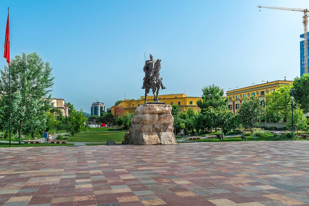 Tirana, Albania - Monument to Skanderbeg on the square in Tirana. Sculpture of the hero of Albania riding a horse on the backdrop of an urban landscape with a green park on a summer day