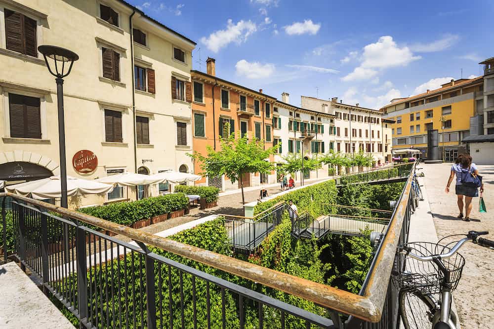VERONA ITALY - Picture from Piazza Cittadella with restaurants trees people and a wide green garden with stairs in a sunny day with clouds. Verona Italy.