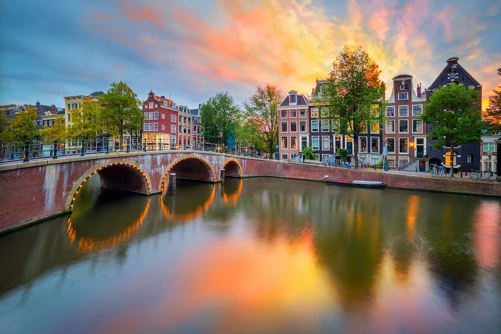 Fantastic sunset sundown sunrise colors in Amsterdam. Panoramic views of the famous old houses, the bridge and the canal in the downtown. Amsterdam, Holland, Netherlands, Europe.