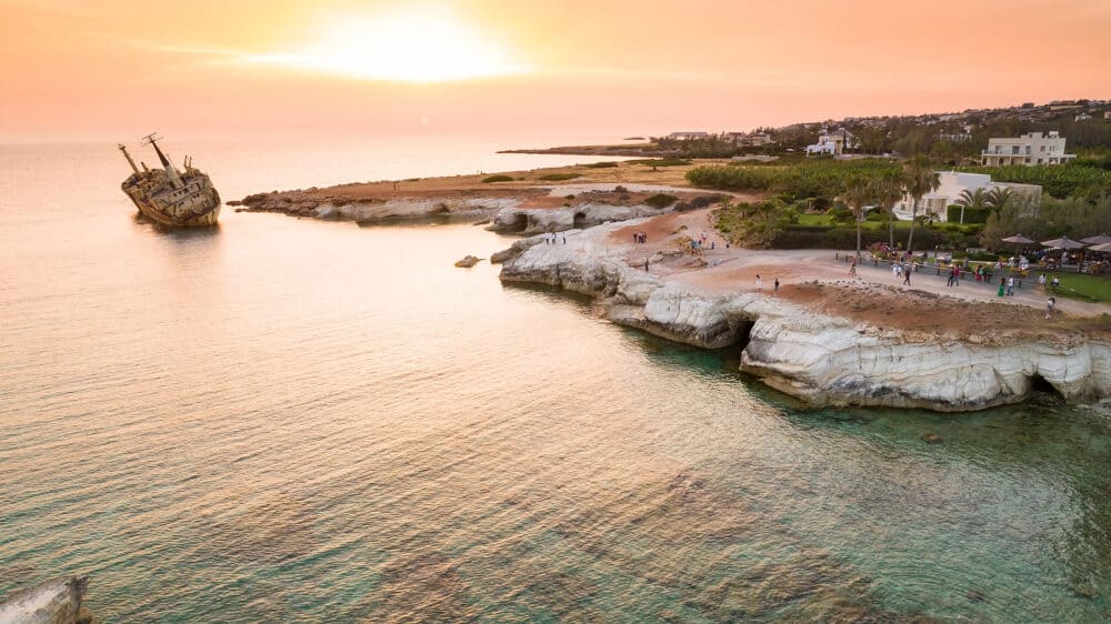 Aerial bird's eye view of the abandoned ship wreck EDRO III in Pegeia, Paphos, Cyprus from above at sunset. The rusty shipwreck stranded on Peyia rocks at sea caves near Coral Bay in Pafos, standing on coast.