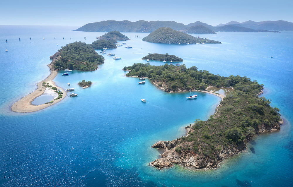 Beautiful landscape aerial view of turkish islands near Fethiye. Lots of sport yachts near islands with open sails.