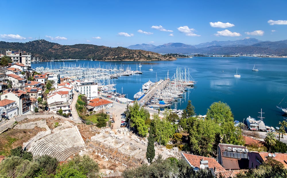 Fethiye, Turkey - View of Fethiye harbor with yachts and boats and mountains. There are ruins of Ancient Theater Antik Tiyatrosu on foreground. Mugla Province.