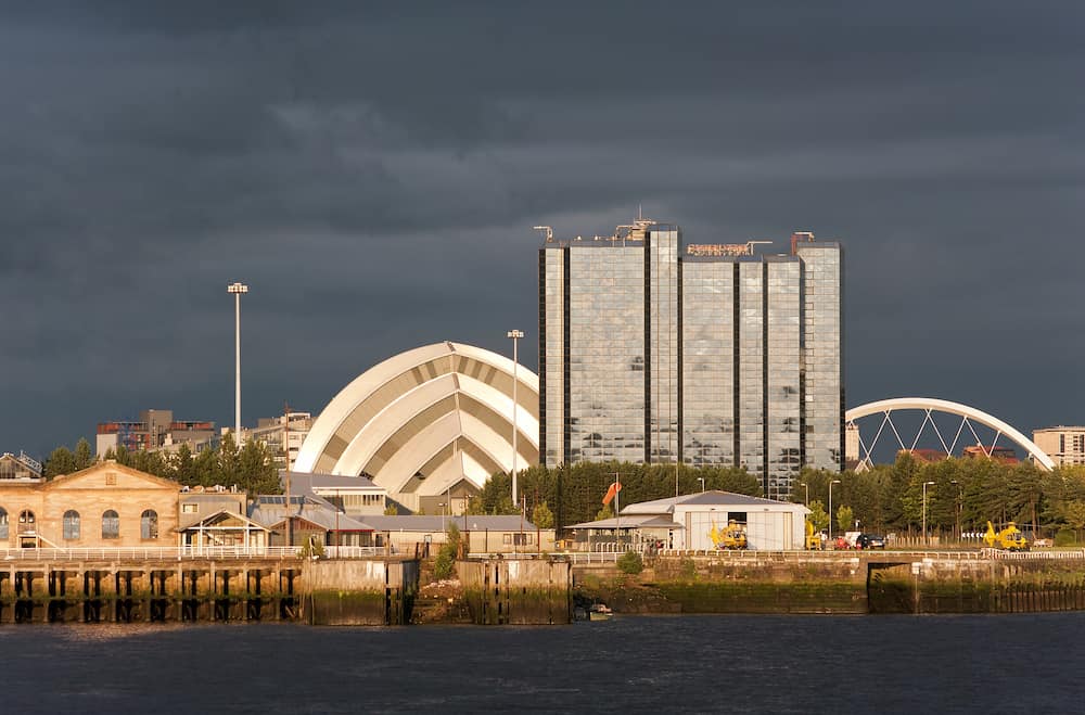 Sunlight on buildings as storm clouds gather beside River Clyde in Glasgow Scotland UK Europe