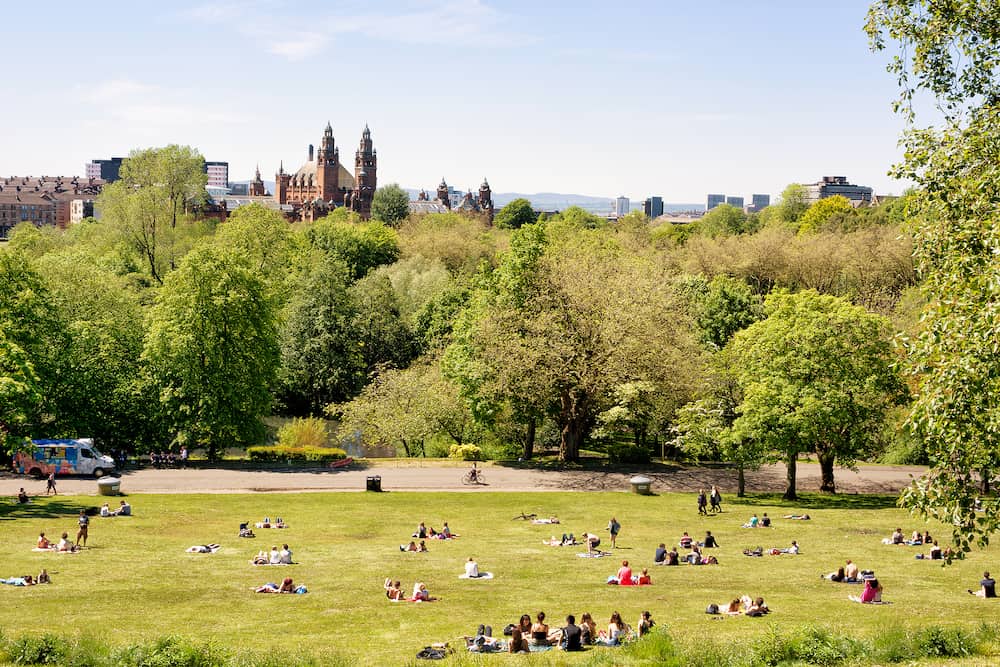 Glasgow Scotland UK: -Young people, students of the University of Glasgow enjoying a warm sunny day on the lawns of Kelvingrove park, Kelvingrove Art Gallery and Museum in the background