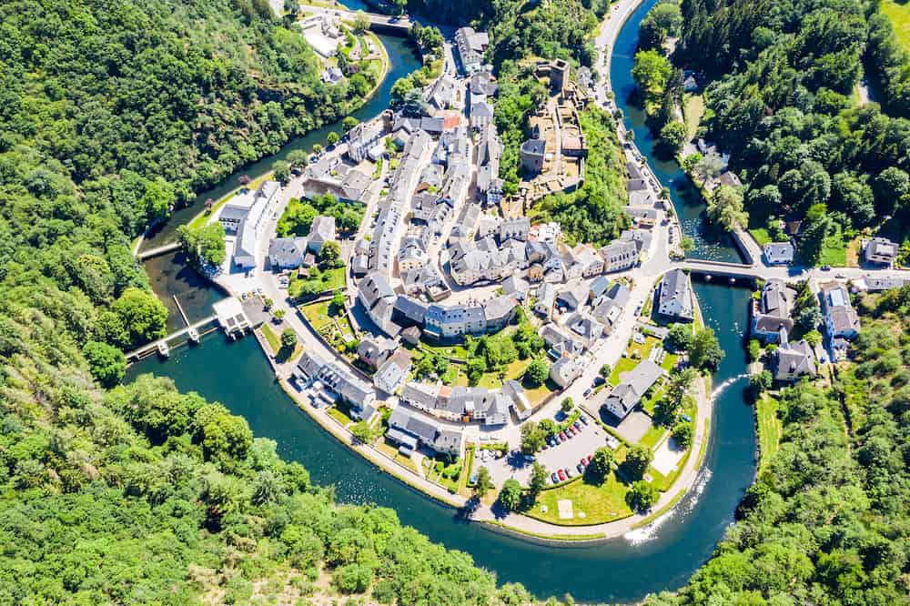 Aerial view of Esch-sur-Sure, medieval town in Luxembourg, dominated by castle, canton Wiltz in Diekirch. Forests of Upper-Sure Nature Park, meander of winding river Sauer, near Upper Sauer Lake.