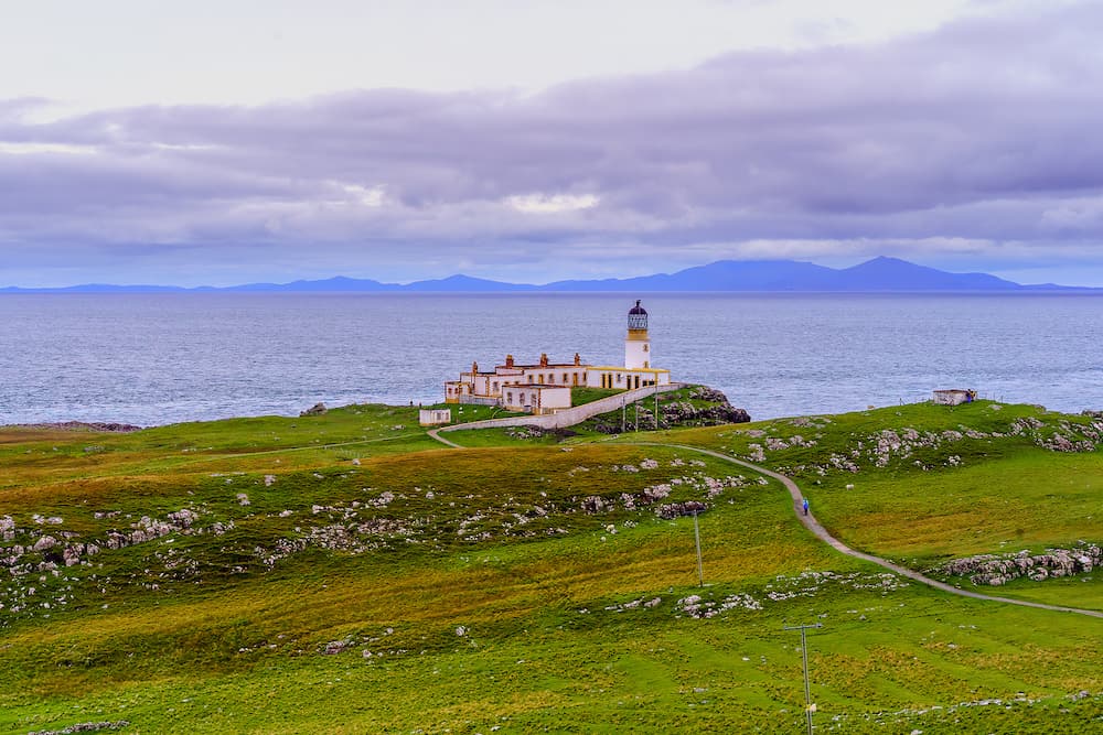 Sunset view of Neist Point Lighthouse, coastal cliffs, and rocks, in the Isle of Skye, Inner Hebrides, Scotland, UK