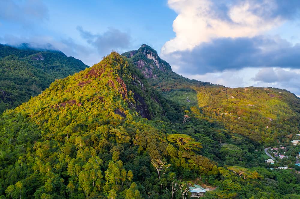 Morne Seychellois National Park aerial view from drone during sunset, golden hour, with lush tropical mountains, Mahe Island, Seychelles.