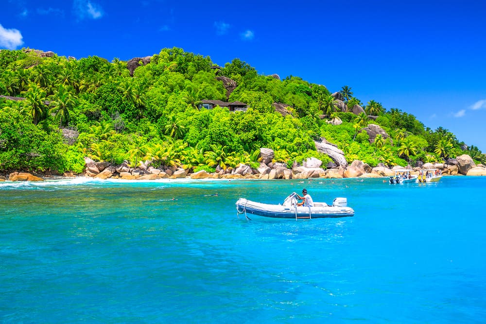 Felicite Island, Seychelles - sailboat, motorboat and snorkelers at Felicite Island Marine Park. Granite boulder stone and turquoise clear sea landscape. Tropical snorleling destination.