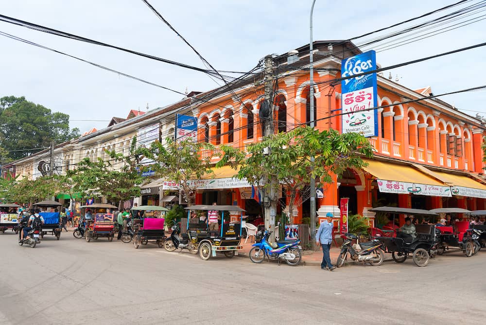 SIEM REAP CAMBODIA - Tourist areas on busy corner intersection with French colonial architecture a Mexican restaurant and Tuk tuk taxi.