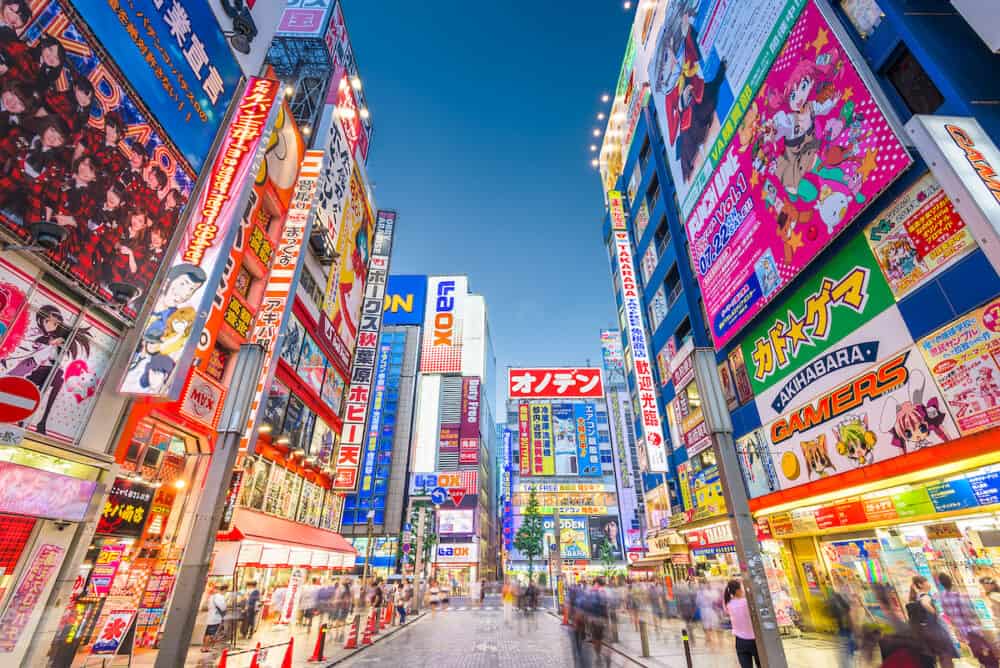 TOKYO, JAPAN - Crowds pass below colorful signs in Akihabara. The historic district electronics has evolved into the shopping area for video games, anime, manga, and computer goods.