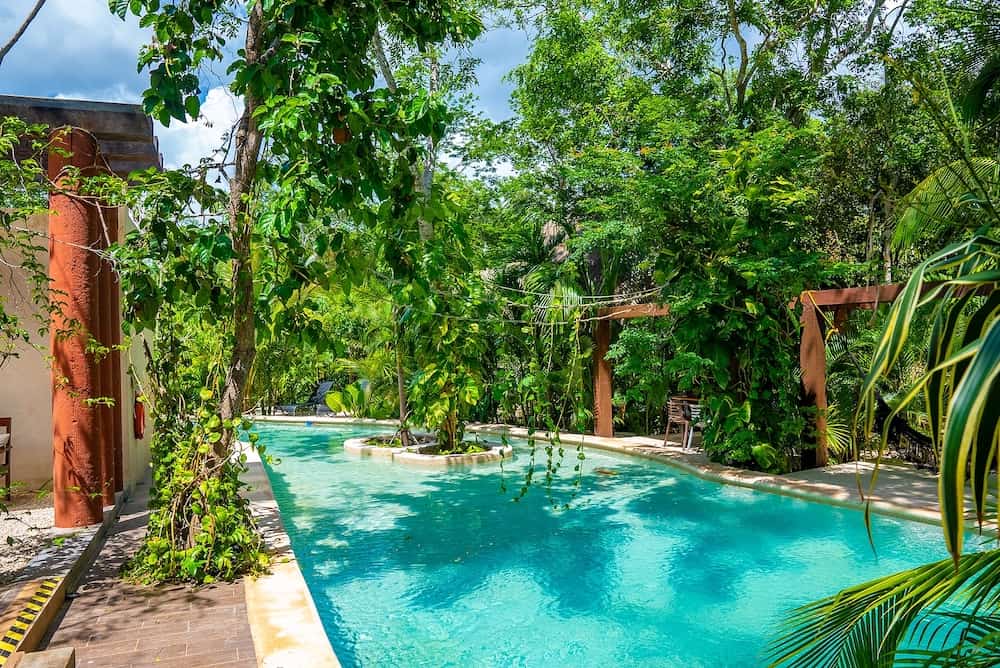 Tranquil swimming pool with trees and hammock at luxury hotel resort