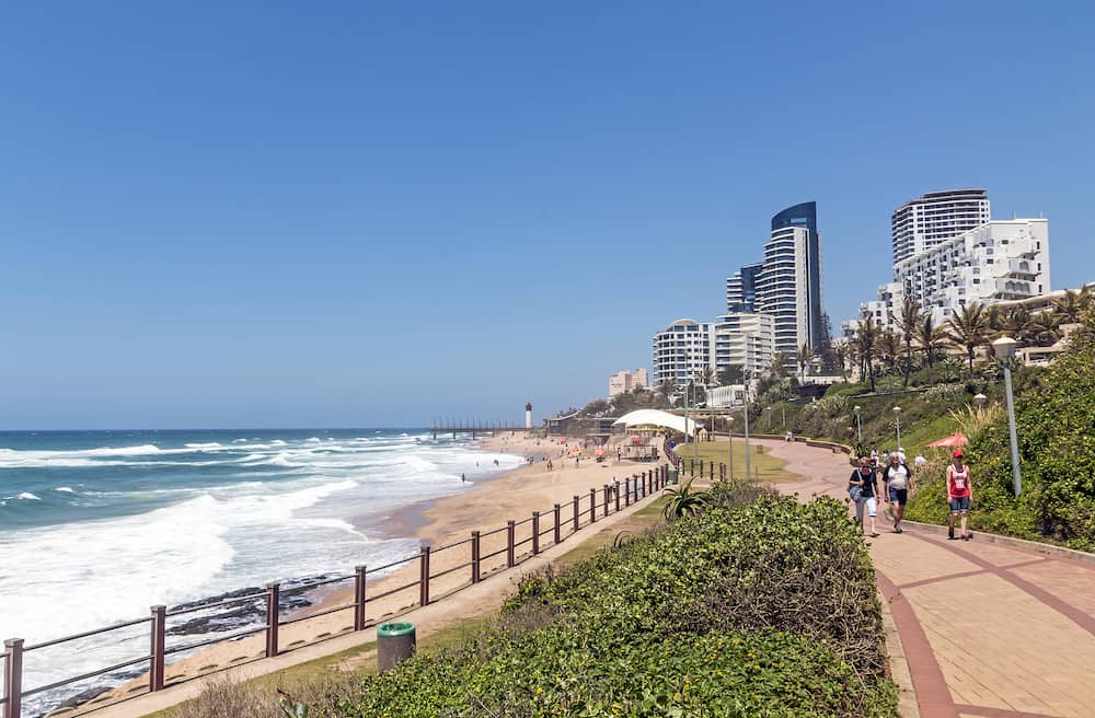 UMHLANGA DURBAN SOUTH AFRICA - Many unknown visitors and promenade on beachfront against coastal commercial and residential city skyline in Umhlanga Durban South Africa