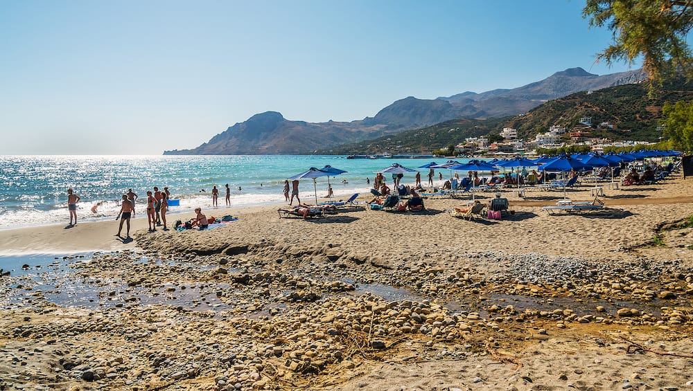 PLAKIAS, CRETE, GREECE - People having rest on sandy beach of Plakias town at Crete island.