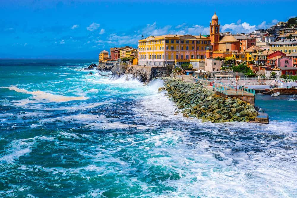 rough sea big waves crash on small port of Nervi in Genoa in Italian Riviera of liguria in beautiful sunny day