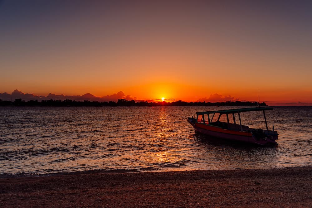 Sunset or sunrise at tropical beach with boat and ocean in Gili Meno island